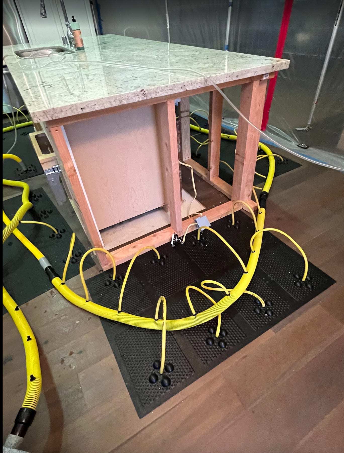 Drying mats and hoses on the floor around a kitchen island frame