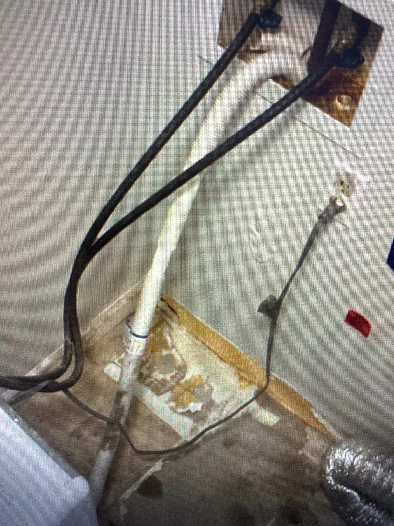Washer supply box with water staining down the wall and floor