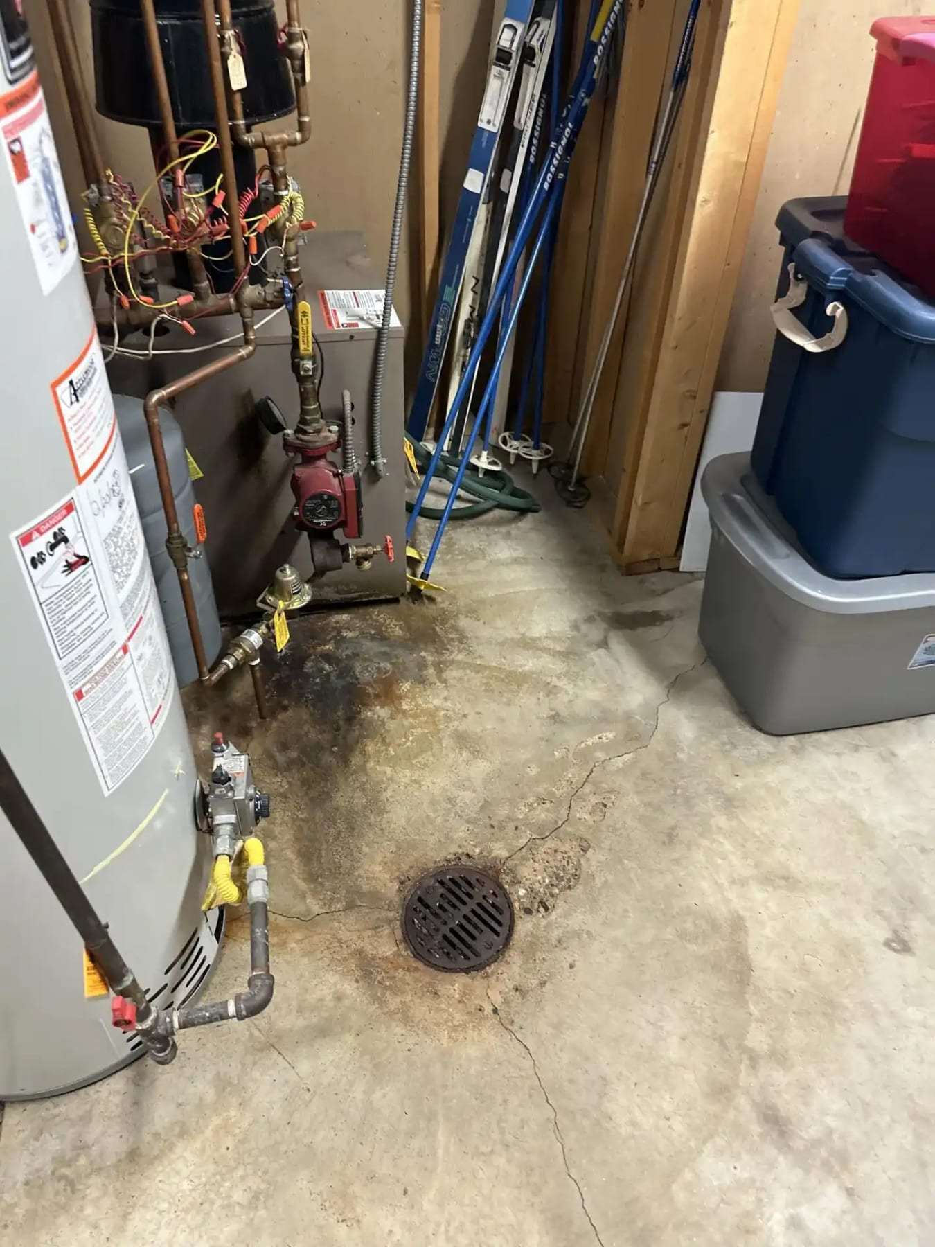 Water heater with a leak at the drain valve beside a floor drain
