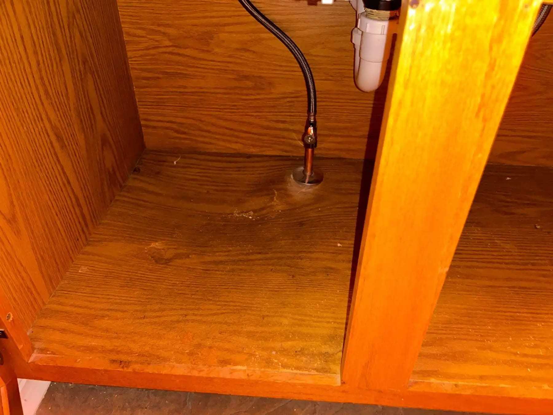 Water staining on the floor of a cabinet under a kitchen sink
